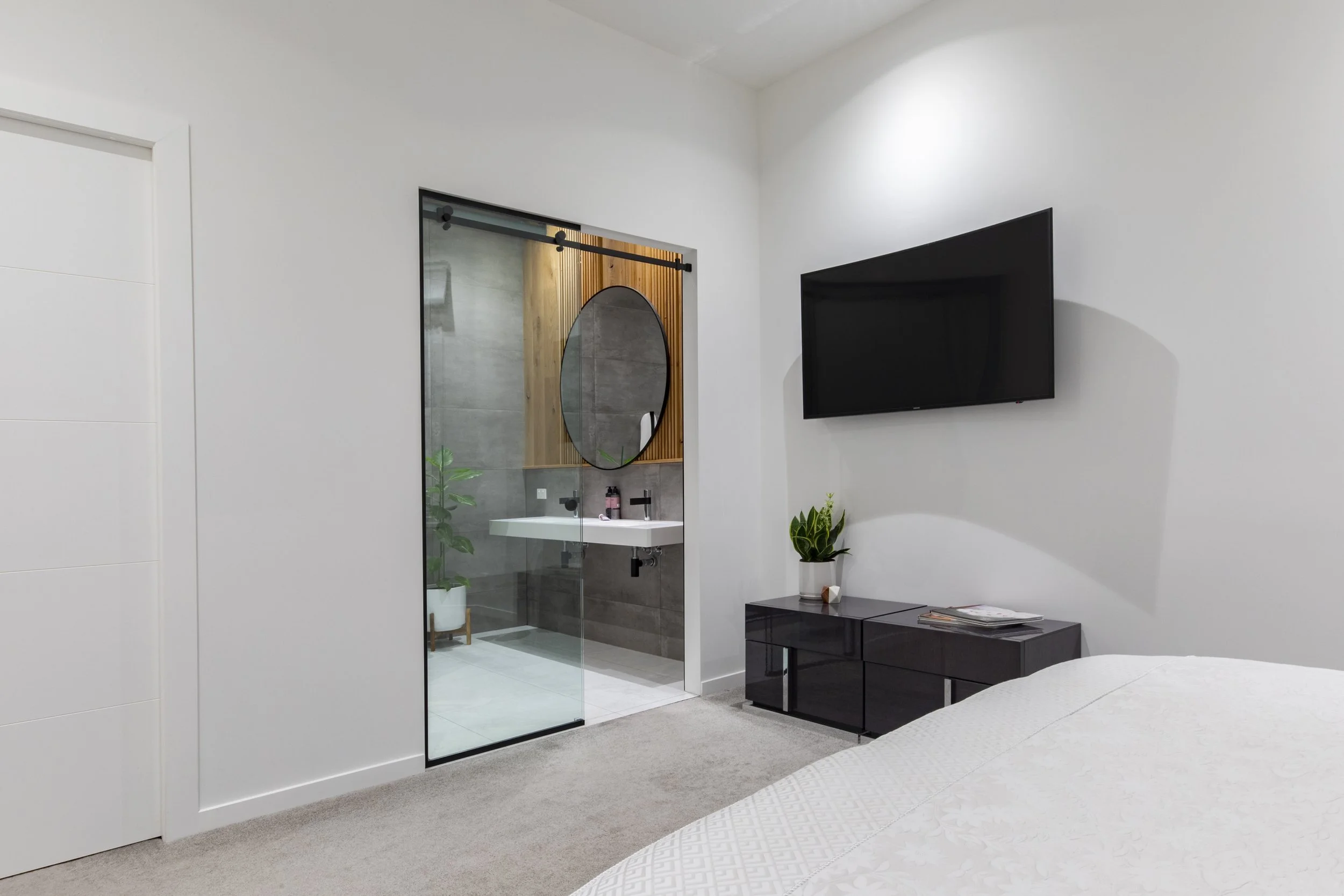 Bedroom with ensuite glass sliding door and wall-mounted TV