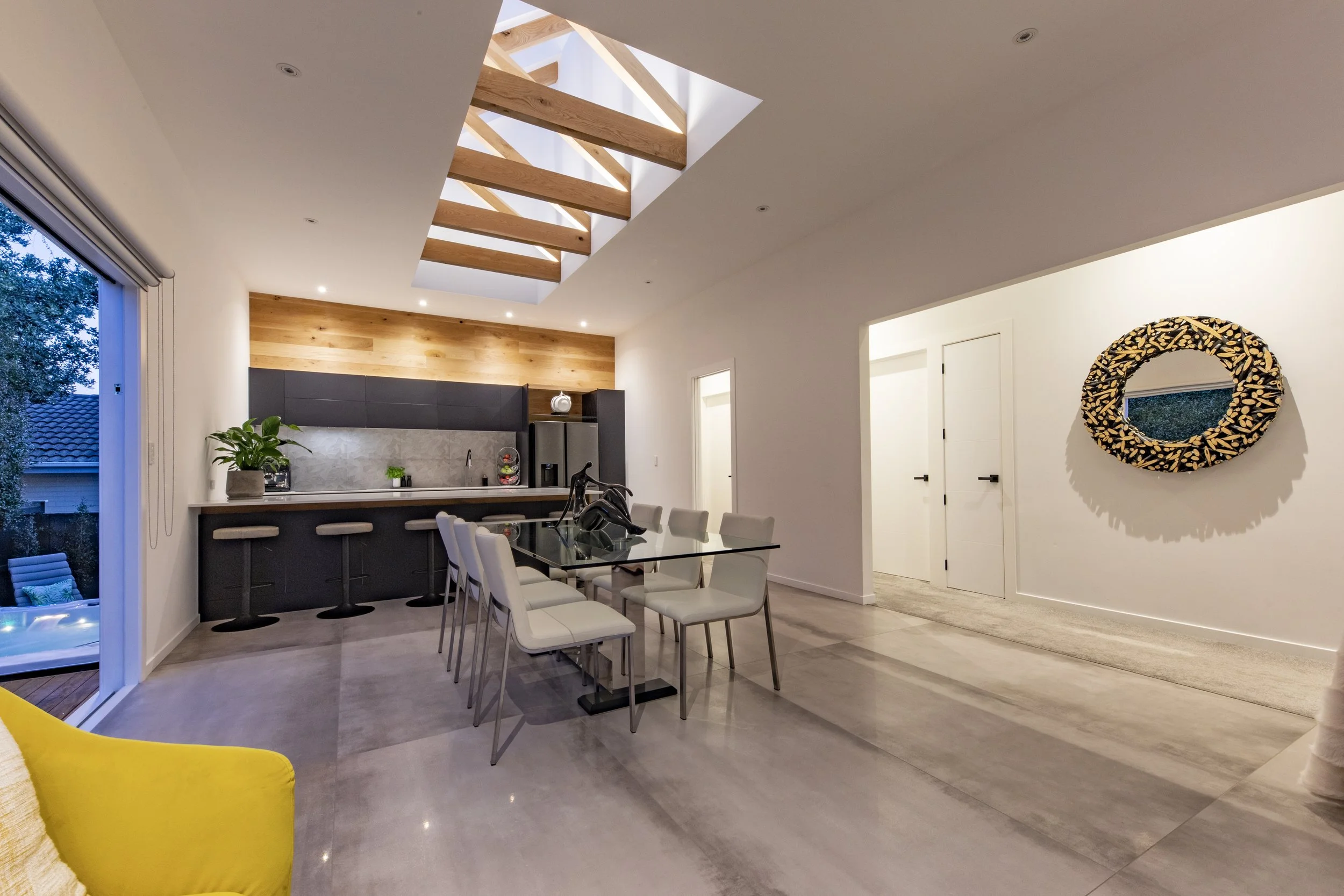 Open-plan kitchen and dining with exposed timber beams and skylight