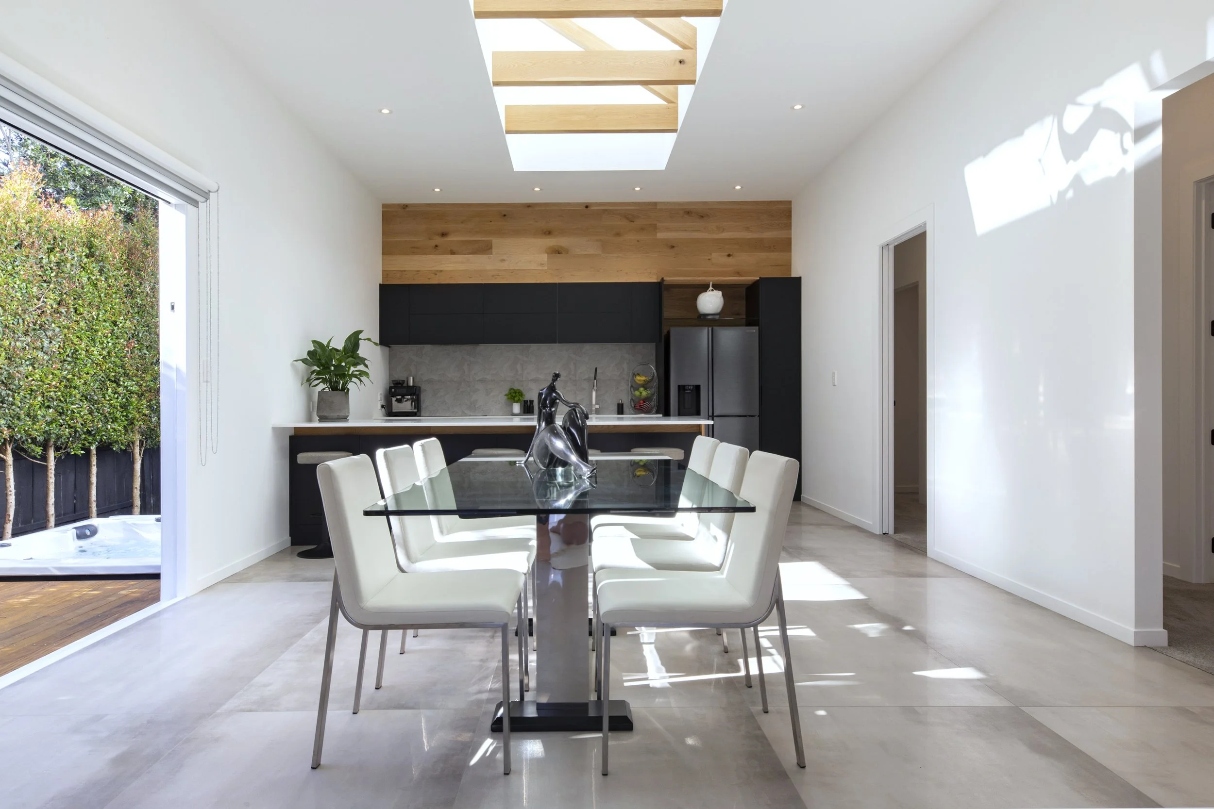 Dining area and dark-toned kitchen with timber skylight detail