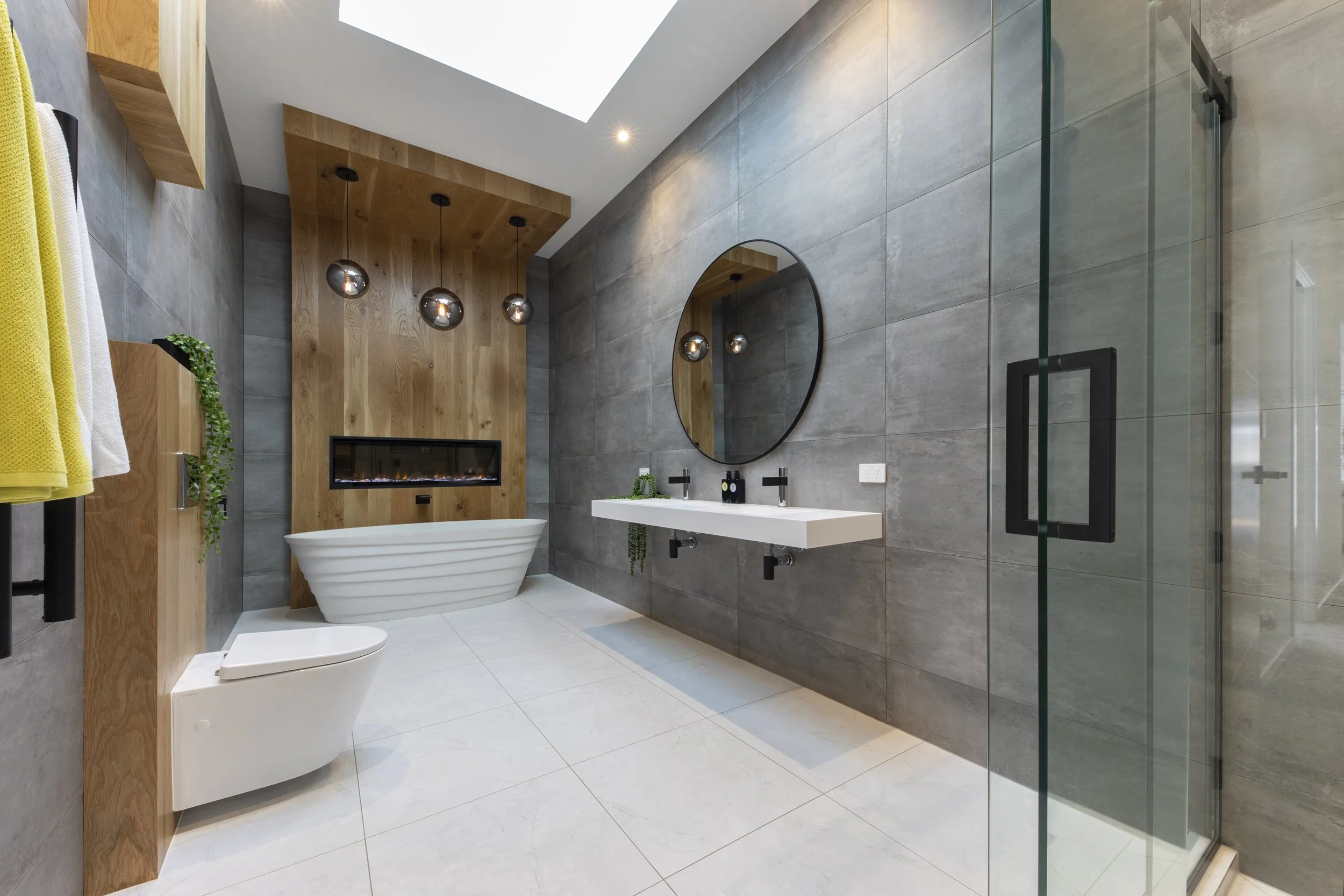 Bathroom with freestanding bath, timber accent wall, and pendant lights