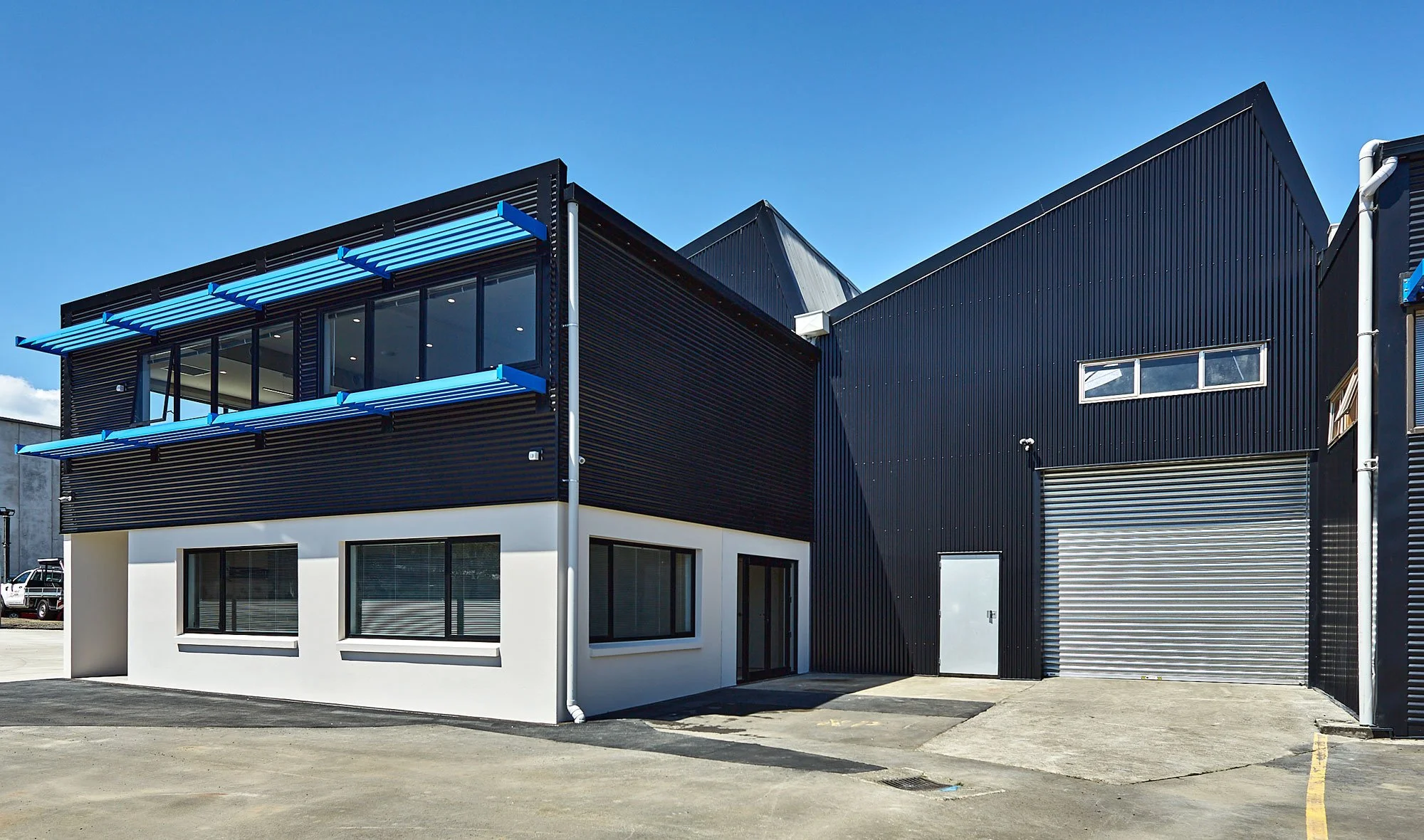 Office block exterior with blue louvres and white ground-floor cladding