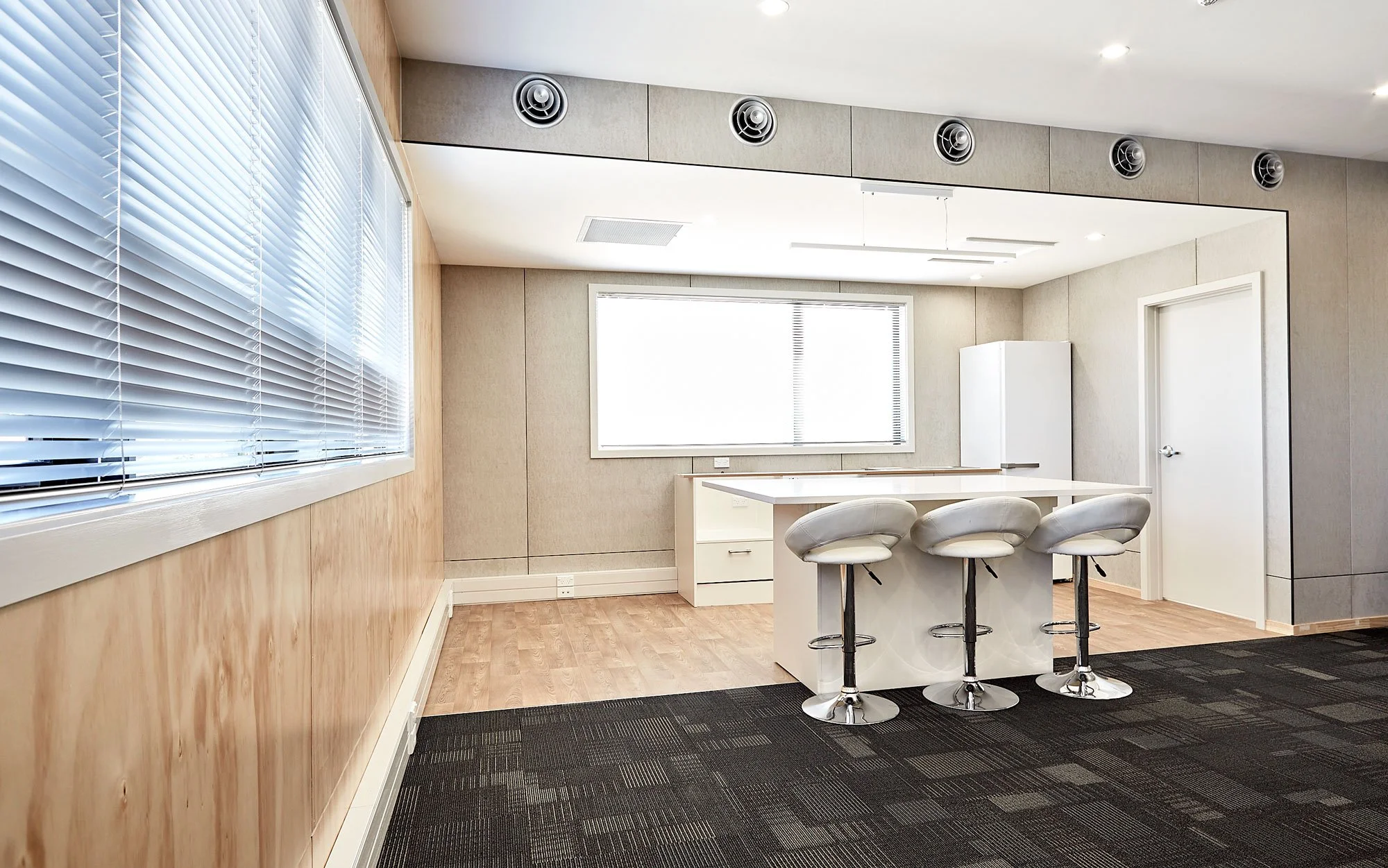 Office kitchen area with bar stools and plywood panelling