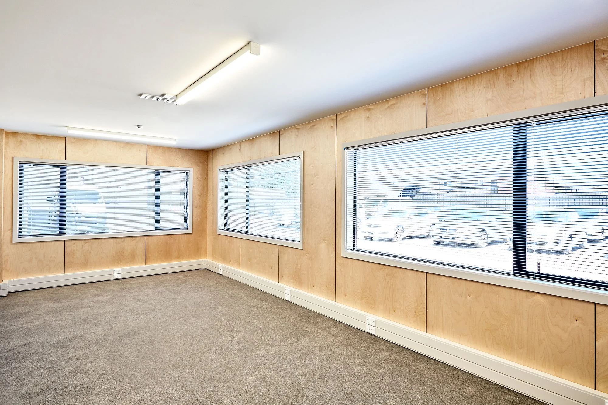 Corner office with plywood walls and venetian blinds